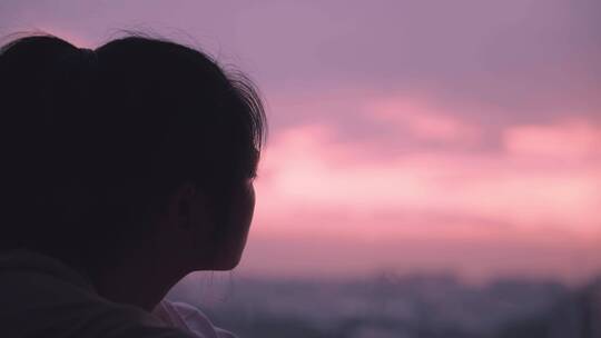 女孩在夕阳下的落地窗边想心事4k视频素材