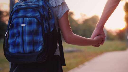 一个年轻人牵着女儿的手去上学