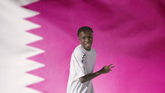 年轻足球运动员在卡塔尔国旗前对着镜头庆祝