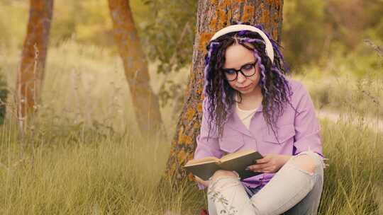 戴眼镜耳机的女子在树旁看书