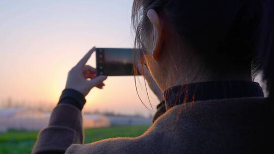 女性使用手机夕阳拍摄照片