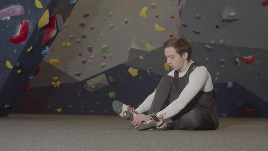 男运动员坐在抱石馆穿登山鞋的特写镜头视频素材模板下载