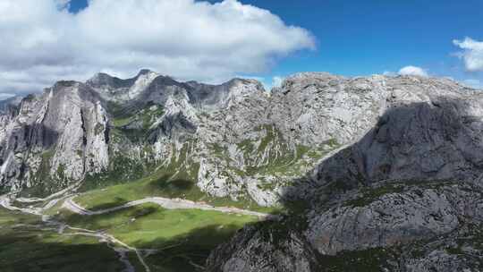 蓝天白云下甘南扎尕那的山脉和山谷中的公路