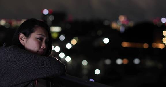 夜晚女人在天台看城市景观