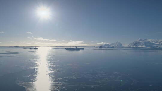 南极洲海洋上空的空中飞行。明亮的太阳