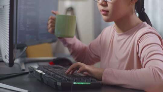 在电脑前喝水的女孩