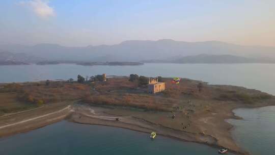 岛上旧建筑的鸟瞰图，日落时的旅游滑翔伞