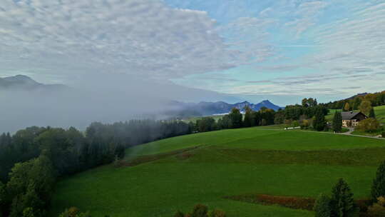 青山上的薄雾云与高山乡村的小屋。