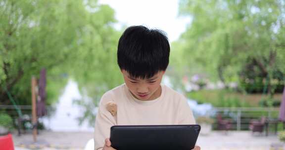 可爱的中国小男孩在户外使用平板电脑