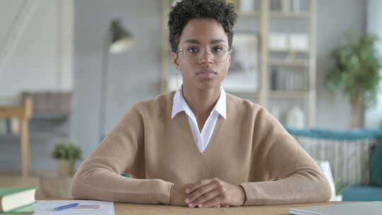 年轻的非洲女孩微笑着坐在她的工作桌旁