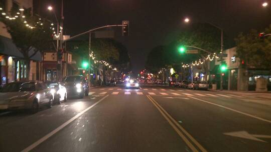 一辆汽车在加利福尼亚州圣莫尼卡的夜晚沿着街道行驶视频素材模板下载