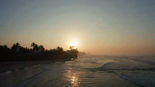斯里兰卡岛南部沙滩上的日出。冲浪者骑在他们的