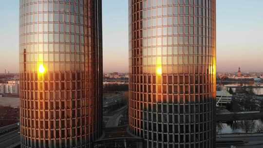 展示了两栋玻璃高层办公楼和公寓楼的空中拍摄，日落反射着i