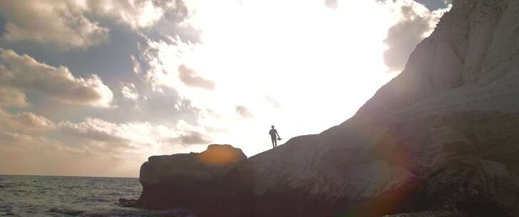 摄影师站在岩石海岸观看太阳