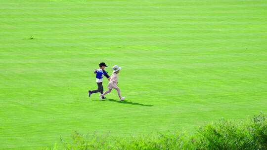 两个小孩在草地上欢快地奔跑