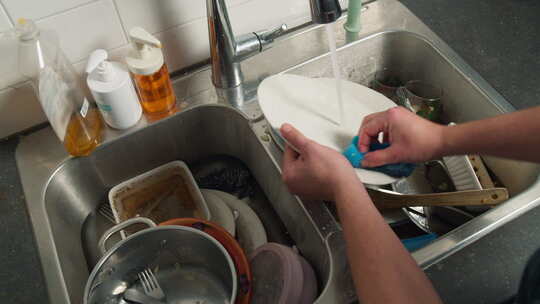 男人在厨房的脏水槽里用手洗碗