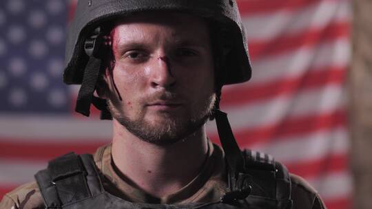 在美国国旗前头上流着血的军人摘下头盔