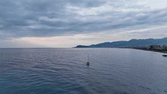 帆船游艇以安静的速度在日落时间到达港口鸟瞰图