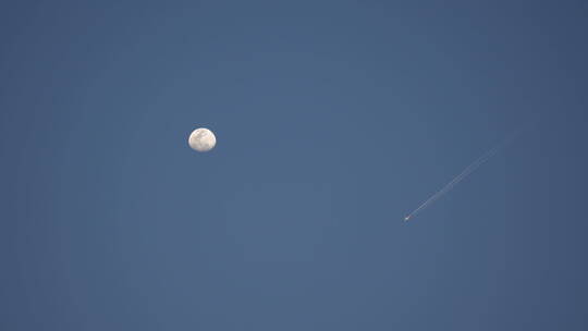 蓝天上的月亮和飞过的飞机