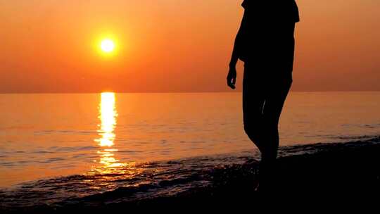 女人海边夕阳下沙滩走路散步剪影