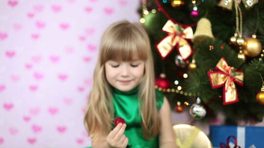 小女孩坐在圣诞树前吃糖果