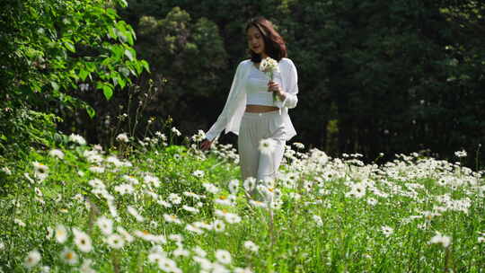 美女手握鲜花漫步草地沐浴阳光慢镜头