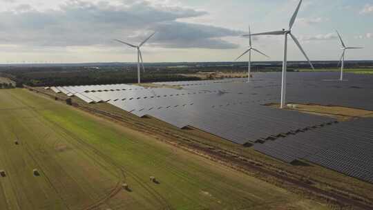 丹麦Holstebro附近农田麦田作物附近的风力涡轮机和太阳能电池。空中Dro视频素材模板下载