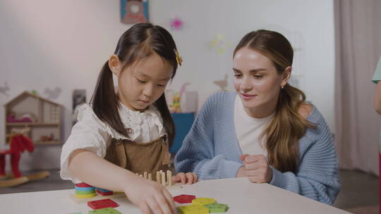 女孩在老师旁玩积木