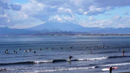 富士山背景下众多人海上冲浪的场景