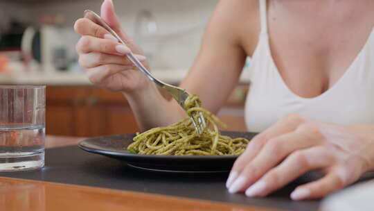 素食女人吃盘子里有DOP罗勒香蒜酱的意大