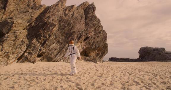 穿着宇航服的男人漫步在沙地上