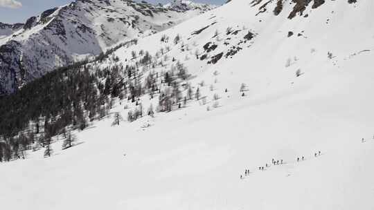 冬季空中俯瞰一群穿着雪鞋沿着雪坡徒步旅行的人视频素材模板下载