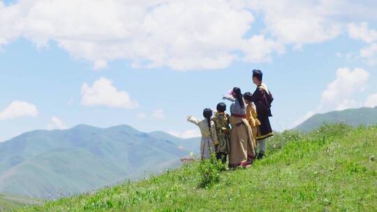 少数民族大人和小孩站在山顶眺望远方