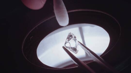 珠宝师在灯光下擦拭钻石的特写镜头