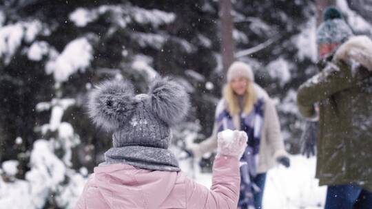 和小孩在雪地里打雪仗的父母