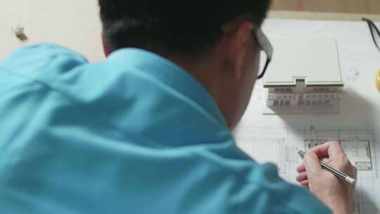 一名男性工程师肩上在办公室绘制蓝图的特写镜头