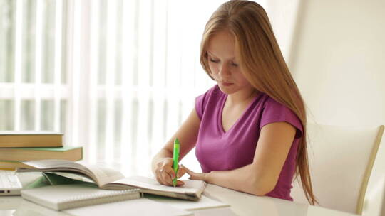 女孩坐在桌子上写练习册