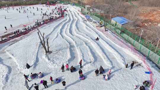 户外滑雪场中许多人在玩雪圈的热闹场景