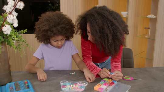 快乐的学龄非裔美国女孩向母亲展示手工项链