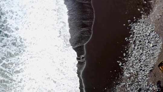 泡沫海浪冲刷着亚速尔群岛的黑色沙滩，垂直俯视图。