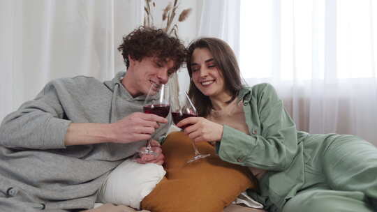 轻松的夫妇在明亮通风的房间里喝着红酒分享
