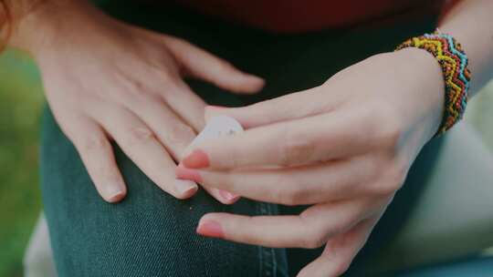 女人在外面用粉色指甲油涂指甲