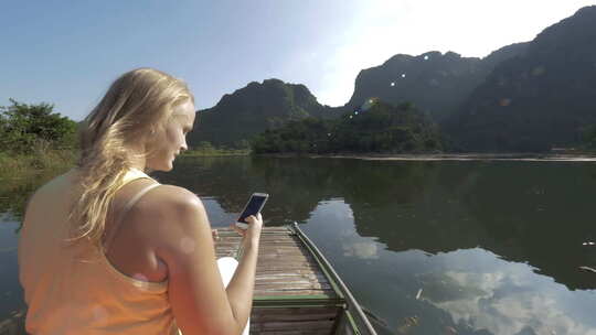 越南长安游船之旅中，一名女子带着手机拍照