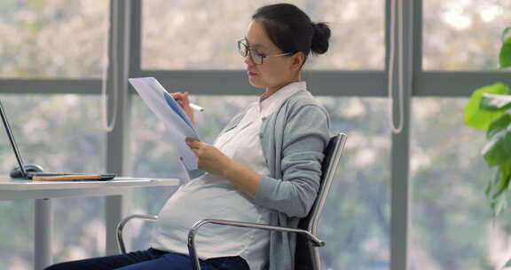 怀孕白领美女在办公室工作看文件