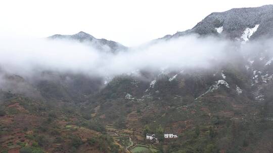 皖南冬天晨雾中的乡村和雪山