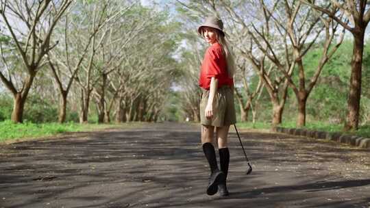 一个拿着高尔夫球杆走路的女人的背影