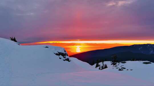 白雪覆盖的山峰，戏剧性的日落天空。加拿大