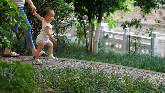 公园里牵着妈妈手走路的小宝宝