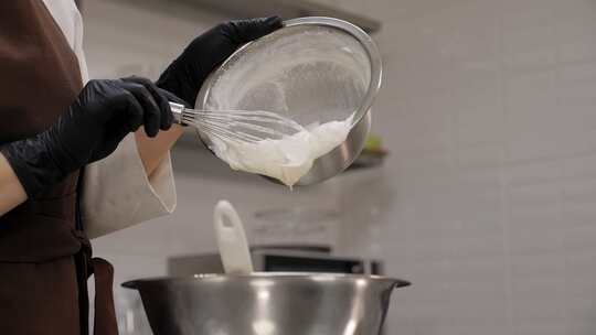 一名女糕点师将鲜奶油倒入金属碗的特写镜头视频素材模板下载