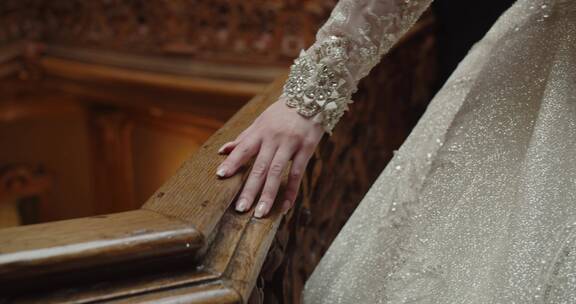 穿着婚纱的新娘手拂过栏杆